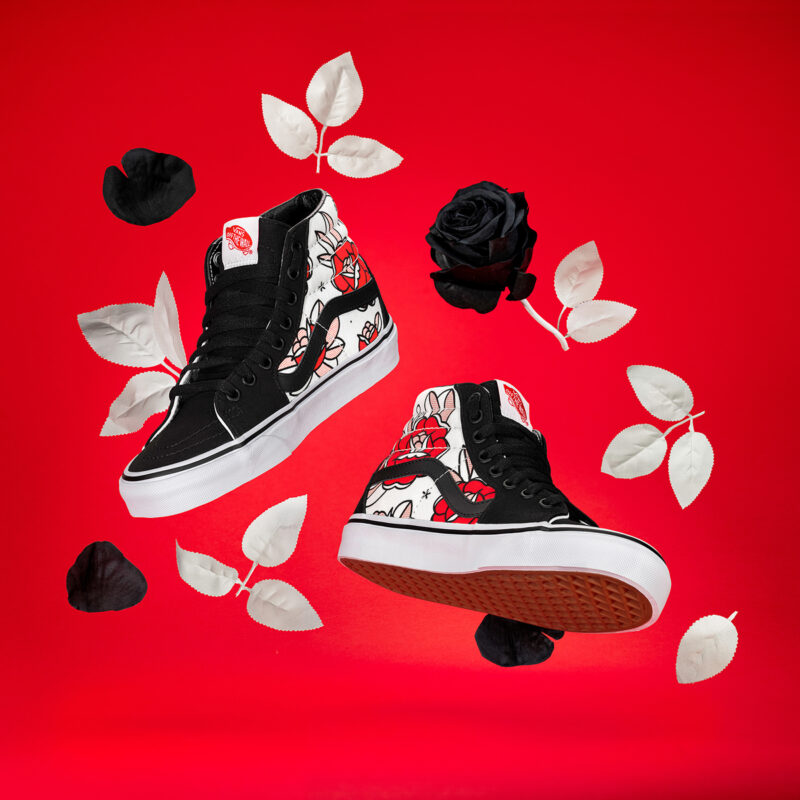 A Photograph of shoes floating surrounded by black and white flowers on a red background