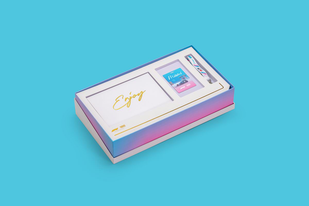 The box set packaging with the lid removed revealing a pass and lanyard with an envelope that says enjoy