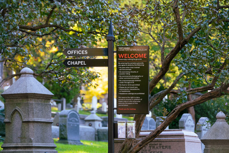 A photo of another welcome sign at a different place in the cemetery with gravestones in the background.