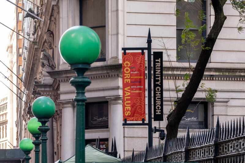 A vinyl sign hanging by the outer gate of the church saying Core Values and Trinity Church.