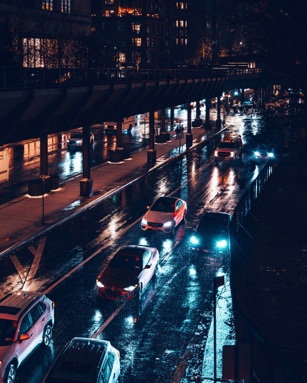 A rainy new york scene showing cars driving down a highway, captured from a bridge above. It features a dark and moody color grade.
