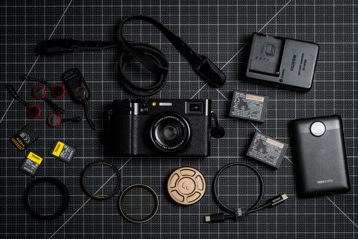 An X100VI camera lying flat surrounded by accessories.