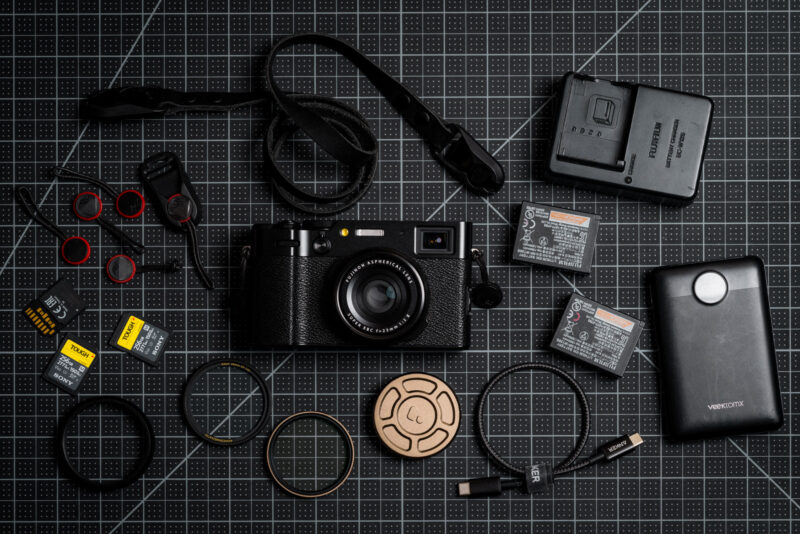An X100VI camera lying flat surrounded by accessories.