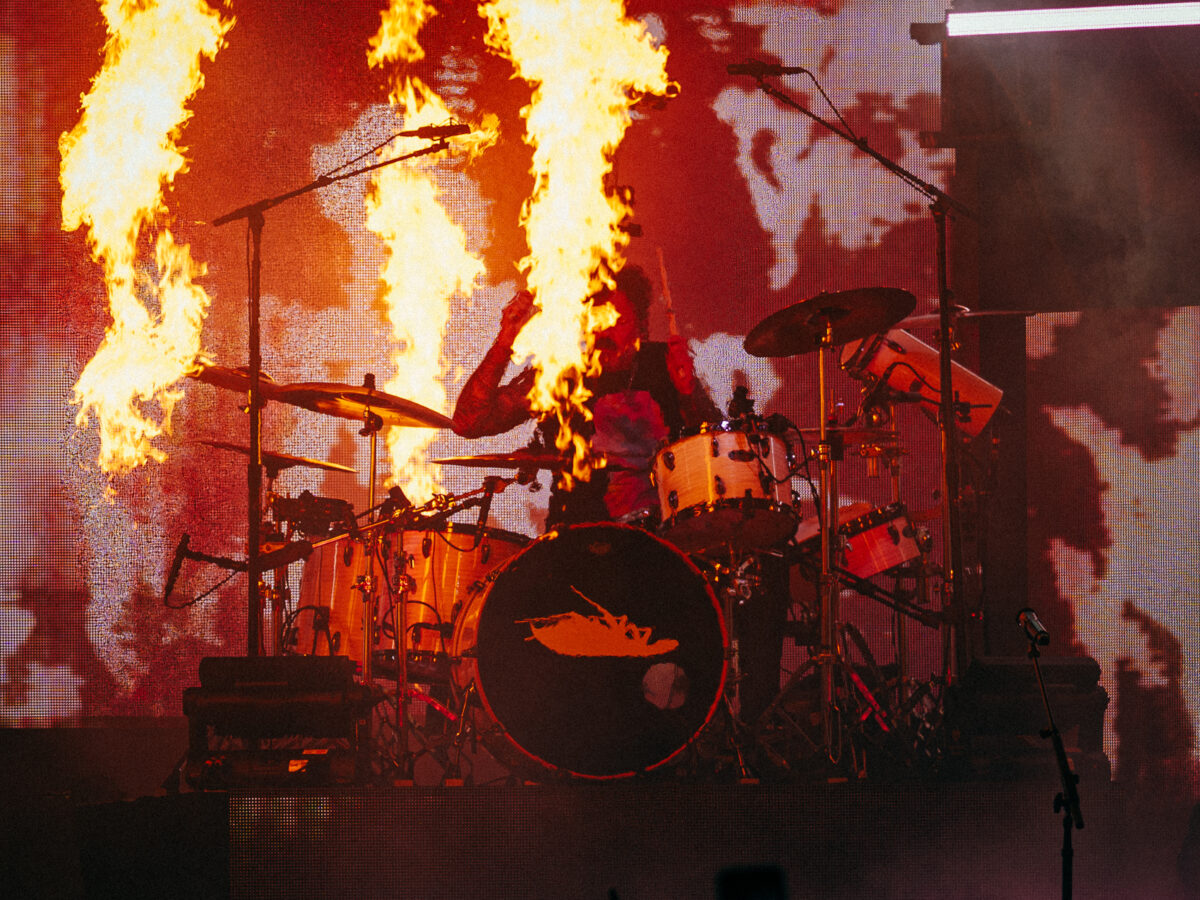 Drummer framed by flames on stage.