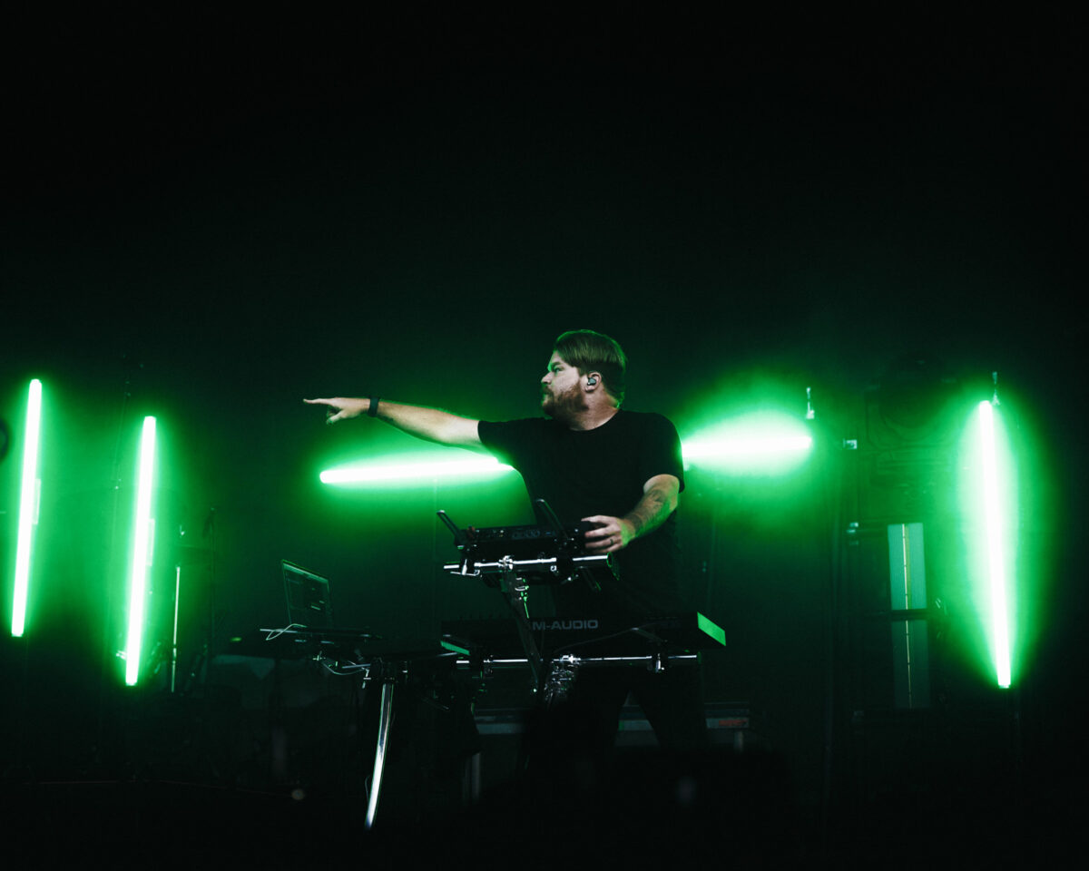 Keyboardist pointing outward under green lighting.