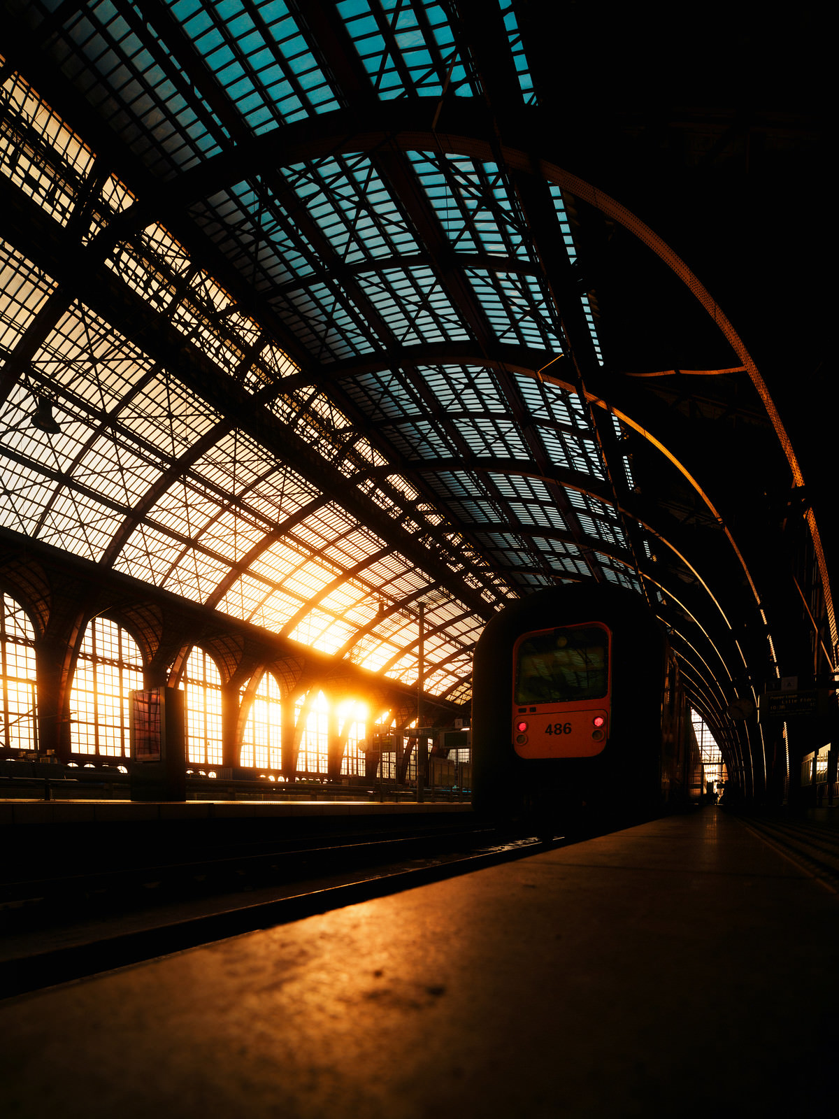 Large train hall with arched windows and warm sunlight