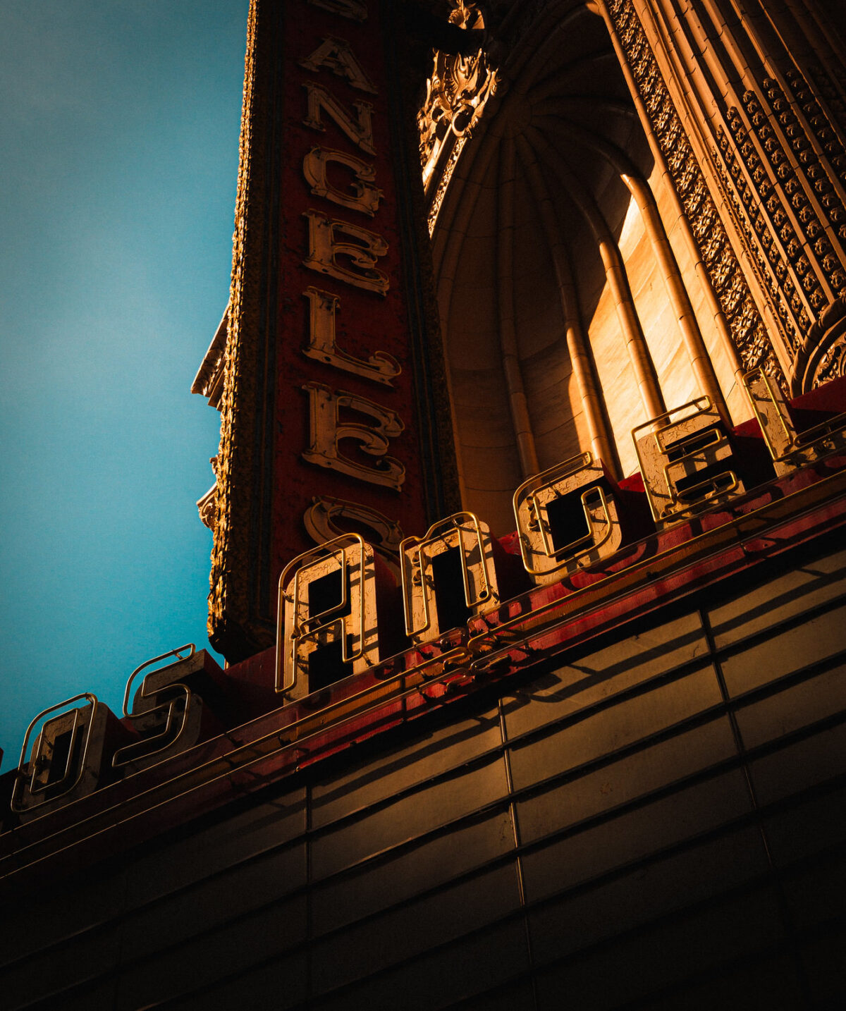 Historic building facade lit by warm sunlight against blue sky