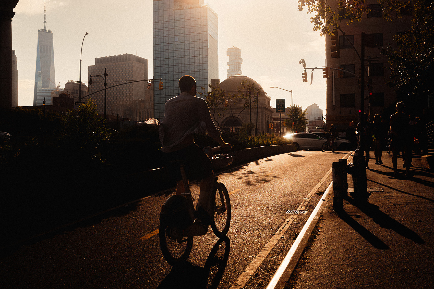 Panoramic Chinatown, NYC street scene with a cyclist in the foreground, a domed building, and One World Trade Center in the hazy distance